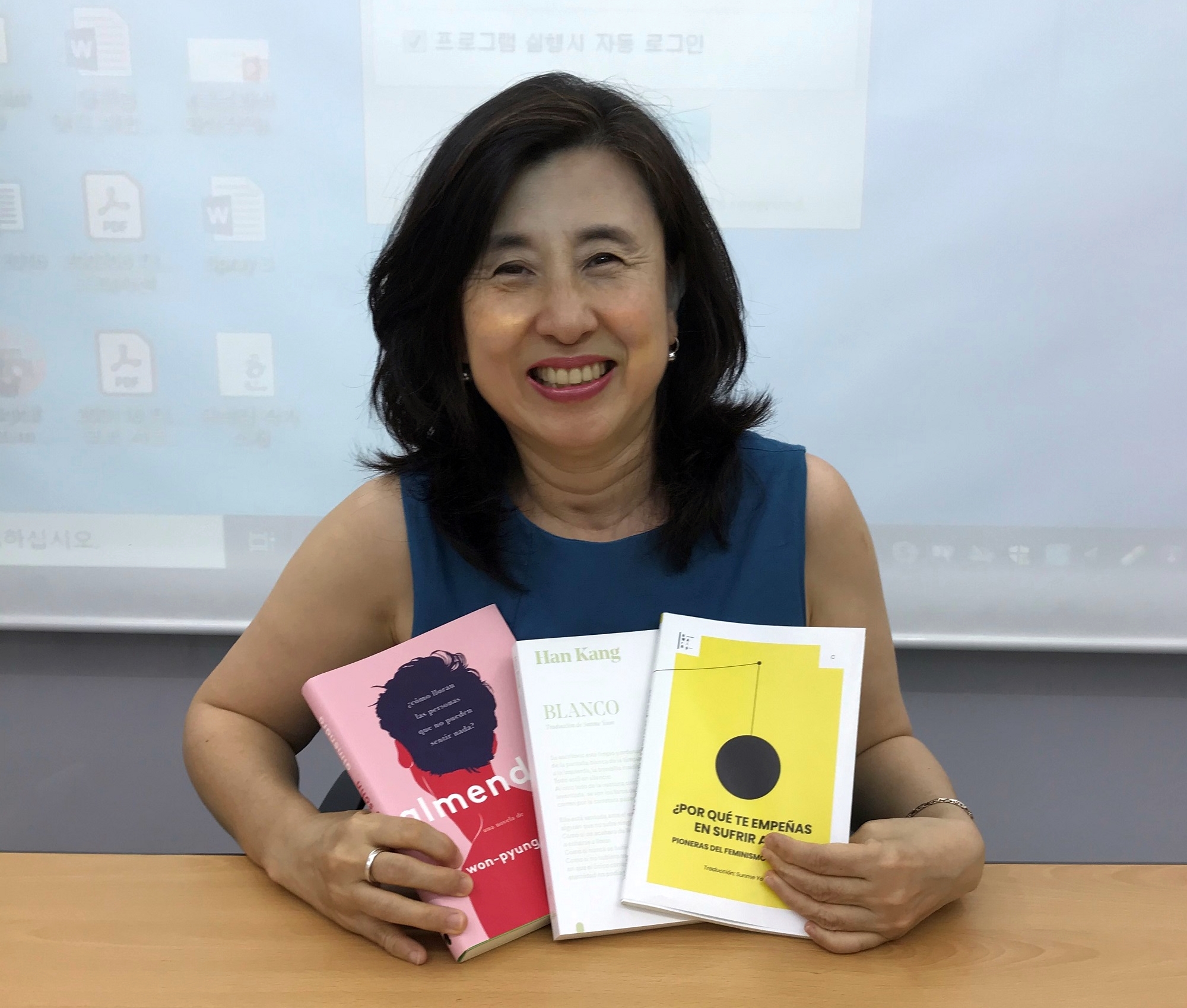 Sunme Yoon sostiene tres de sus más recientes traducciones al español. De izquierda a derecha: “Almendra”, “Blanco”, y “¿Por qué te empeñas en sufrir así?: Pioneras del feminismo coreano”. | Sunme Yoon
