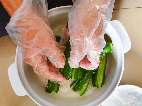 Chà xát đều dưa chuột đã bổ dọc làm tư từ trong ra ngoài bằng muối hạt. (Ảnh: Vũ Đỗ Hải Hà)