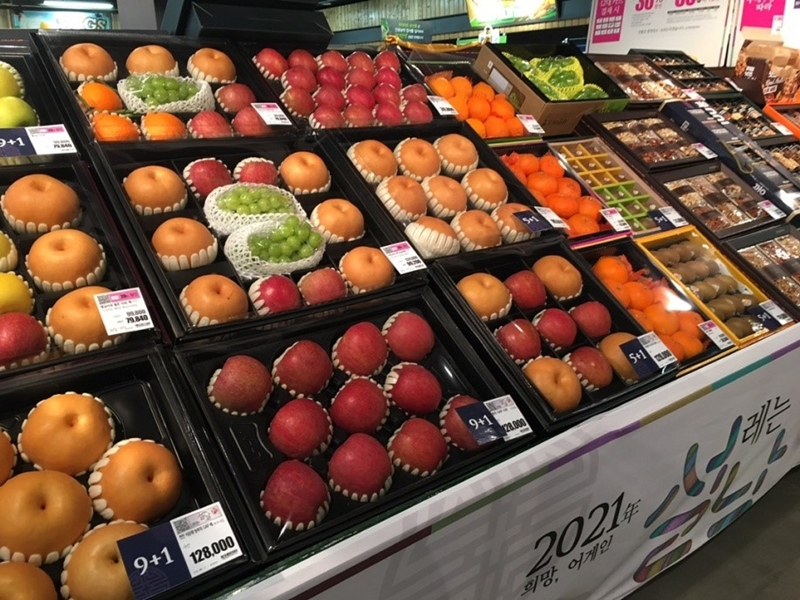 果物セット。りんごの箱に見える９+１の表示は9箱買えば１箱おまけでついてくるという意味だ。