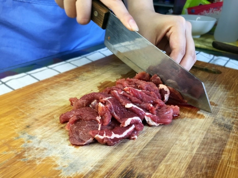 Ta xắt thịt bò thành các lát mỏng. (Ảnh: Lưu Hoàng Nhi)