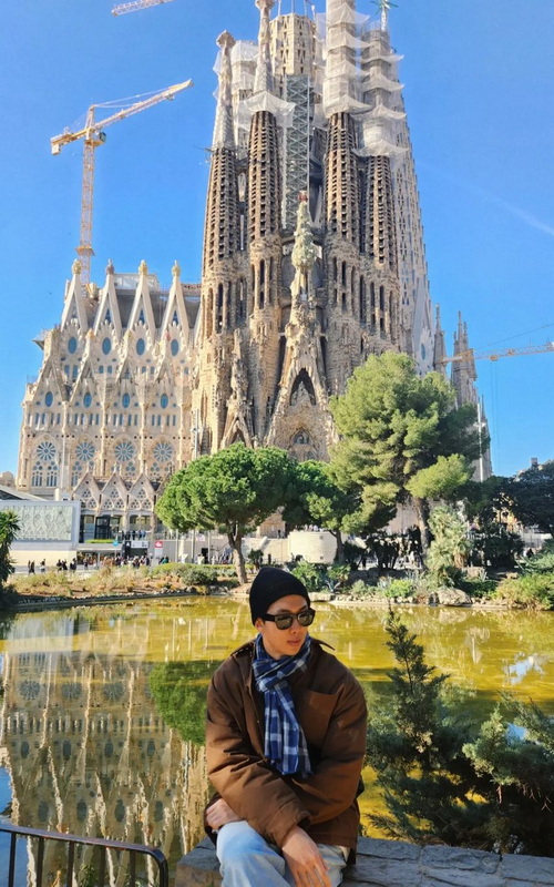El líder de la banda BTS, RM posa en frente de la catedral de la Sagrada Familia, en Barcelona, durante su viaje a España para promocionar su nuevo álbum en solitario. | Cuenta oficial de RM en Instagram
