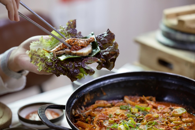 鳀鱼菜包饭的吃法是在生菜里包上白切猪肉、小菜和佐料。韩宣网记者金淳株 摄