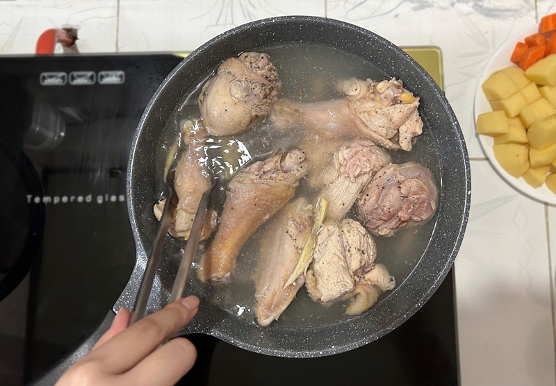 Chần gà trong nước sôi và gừng để khử bớt mùi của thịt gà. (Ảnh: Lưu Hoàng Nhi)