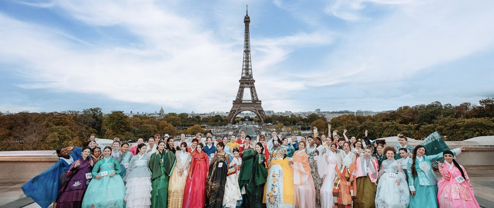 Les participantes, après la première sélection, se rassemblent pour une photo de groupe devant la Tour Eiffel.
