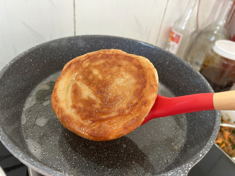 Rán vàng đều hai mặt bánh và lần lượt rán những chiếc bánh còn lại. (Ảnh: Lưu Hoàng Nhi)