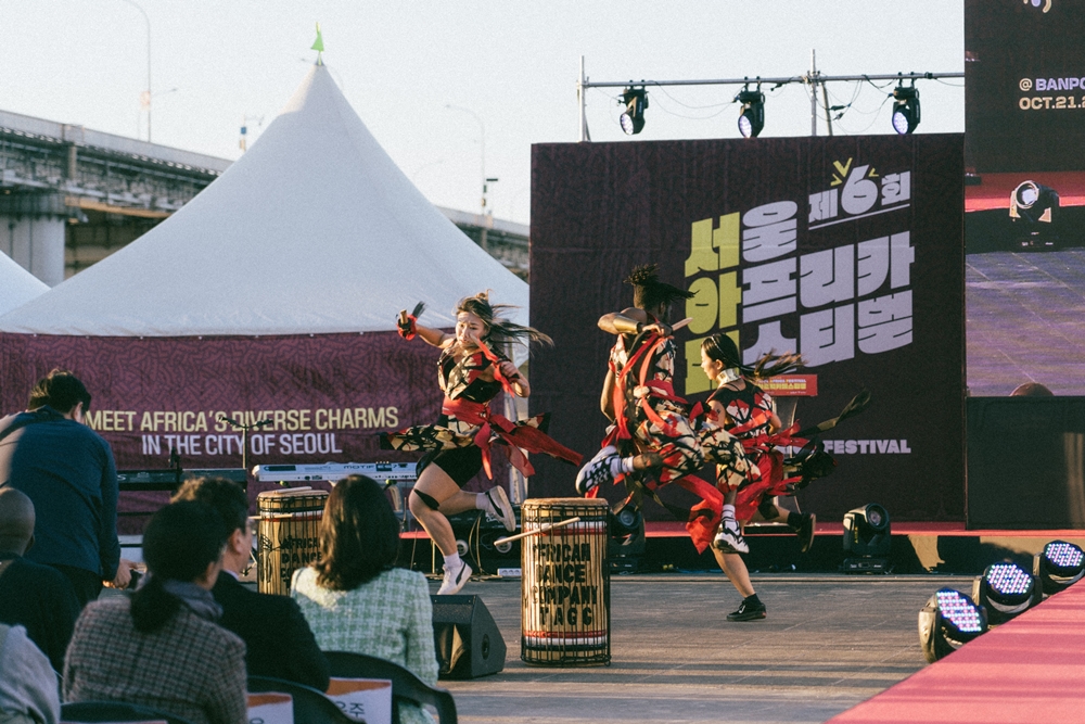 Danseurs du groupe TAGG arborant un pagne africain conçu d'après le costume du Jinju Geommu, exécutant la danse de l'épée d'inspiration coréenne et béninoise, tirée du film « Fight Like a Girl ».