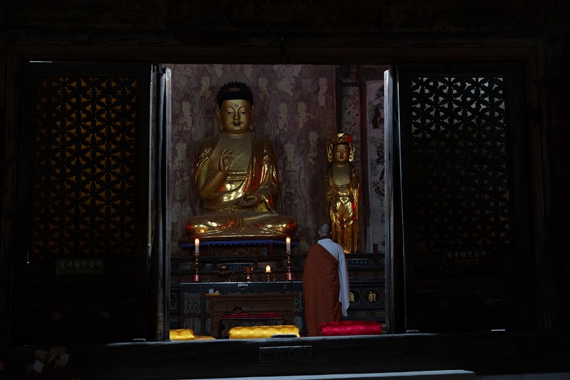 Монах на службе делает поклоны перед статуей Будды в храме Пульгукса. / Фото: KOCIS