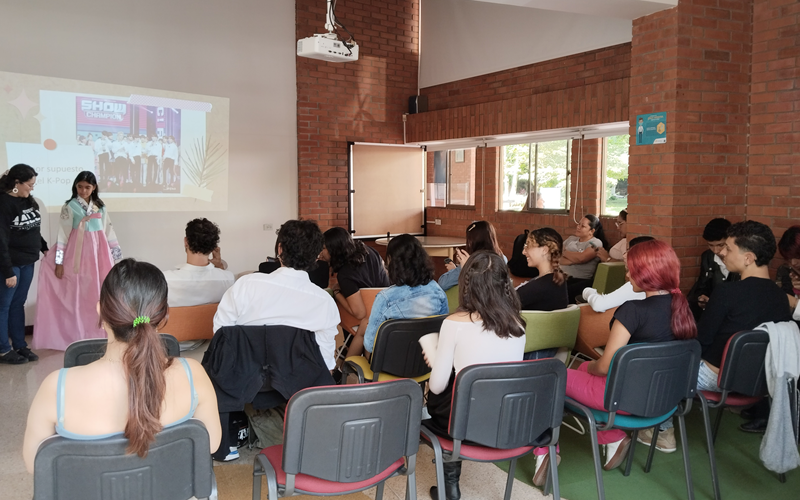La foto muestra a los asistentes escuchando el conversatorio sobre la introducción de la ola coreana en Colombia, durante la Semana del Idioma, la Cultura y las Artes. Al concluir el evento, se realizó un sorteo de productos coreanos, dejando a los participantes sumamente felices. 