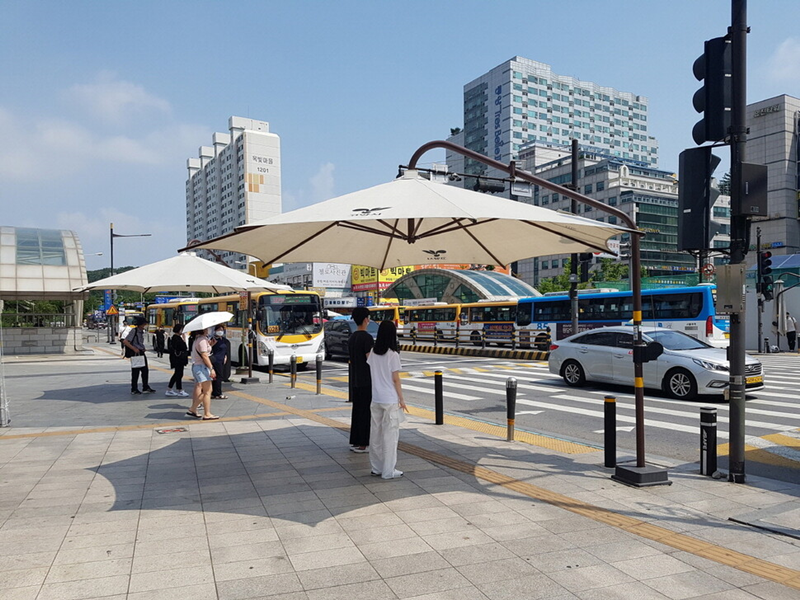  La foto muestra a unos transeúntes protegiéndose del sol en el parasol instalado en una calle de la ciudad de goyang. | Ciudad de goyang
