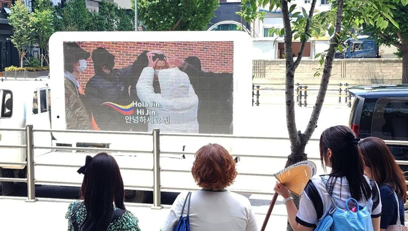 El 12 de junio, los transeúntes observan un video conmemorativo sobre los momentos más icónicos de la carrera de Jin y la trayectoria de BTS, trasmitido en un camión publicitario en Corea, frente al edificio de HYBE, la agencia de BTS, en la capital surcoreana. | Cuenta oficial de ARMY Colombia en Instagram 