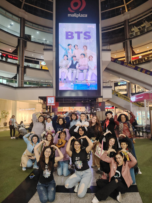 Unas fanáticas de BTS se toman una foto conmemorativa en frente del cartel de bienvenida a Jin, instalado en el centro comercial Mall Plaza NQS, en Bogotá, Colombia. | Maryuri soley Peña Molano 