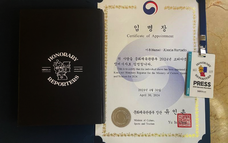 La foto muestra el certificado de nombramiento de la reportera honoraria de Korea.net Alexia Hurtado y el gafete de prensa del programa. 