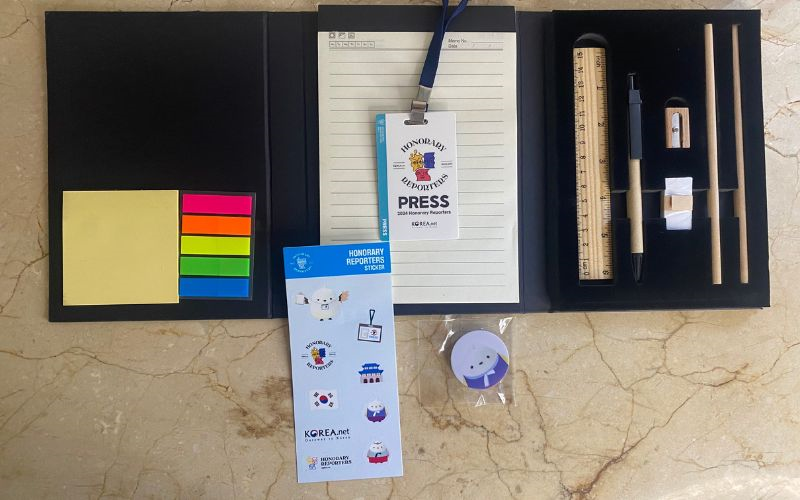 La foto muestra todos los productos de papelería y el gafete de prensa de los kits que fueron entregados a los todos los reporteros honorarios de Korea.net 