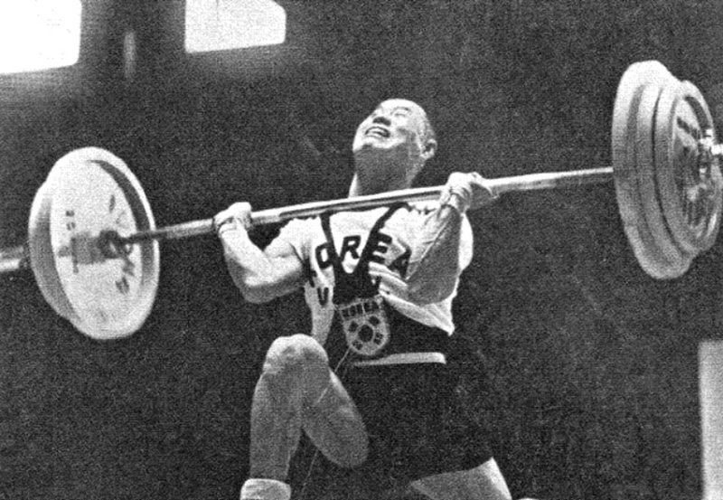 El deportista Kim Seong-jip, ganador de la medalla de bronce en la categoría masculina de levantamiento de pesas en los Juegos Olímpicos de Helsinki en 1952, porta una camisa con el nombre ´Corea´ y un enterizo que lleva la bandera en la parte delantera. | Comité Deportivo y Olímpico de Corea 