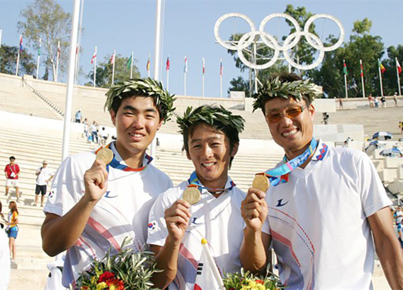 Los atletas olímpicos de tiro con arco de Corea lucen sus medallas de oro, durante la ceremonia de premiación de los Juegos Olímpicos de Atenas en 2004. | Korea.net DB 