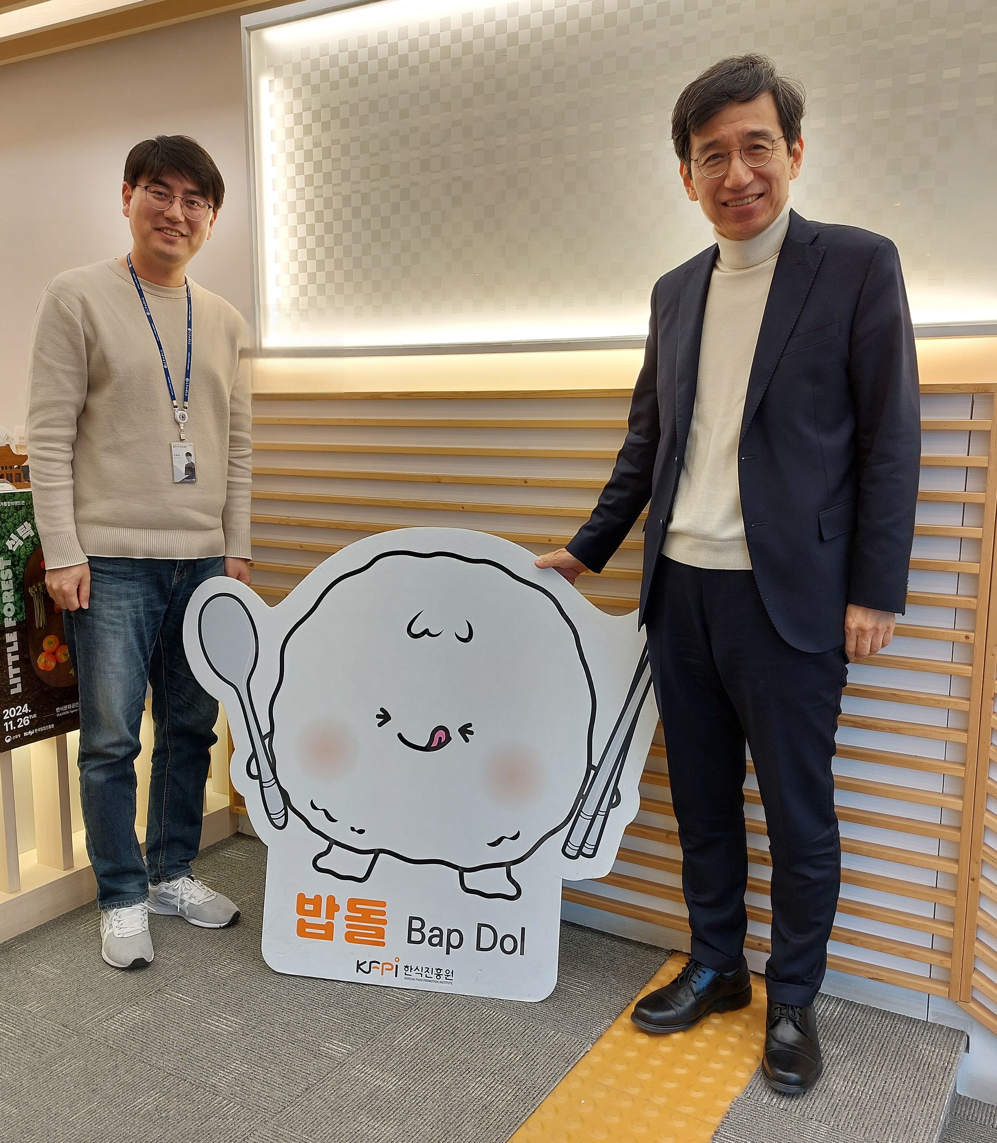 John Hae-Oung (à droite) et son collègue, posant devant Bap Dol, mascotte du Korean Food Promotion Institute. © Emmanuelle Fourneyron