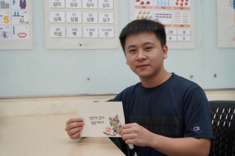 Bạn Hoàng Đình Tâm (học viên lớp Hội thoại) cùng tác phẩm thư pháp tiếng Hàn của mình. (Ảnh: Học viện King Sejong Hồ Chí Minh 2)