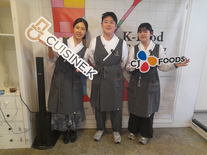 De izquierda a derecha de la imagen encontramos a la chef Lee YeonJu sosteniendo un cartel de Cuisine.K, el chef Lee KyoungWoon, y la chef Choi SuBin sosteniendo un cartel de CJ Foods. | Celia Algaba