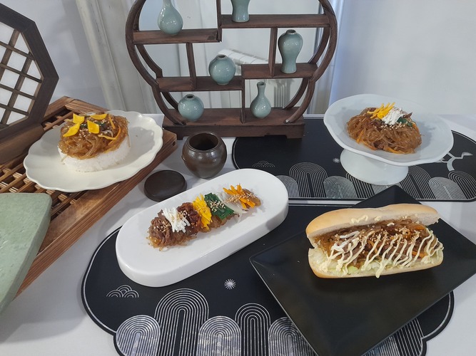 Se muestra japchae servido con arroz, decorado con yema de huevo en forma de rombos; Japchae emplatado al estilo chef, con los ingredientes alineados —ternera, clara, setas, yema, cebollino, cebolla y zanahoria— y una línea de sésamo blanco; Japchae servido en pan, con mayonesa al gochujang y lechuga crujiente; y el emplatado estilo 'de madre'. | Celia Algaba