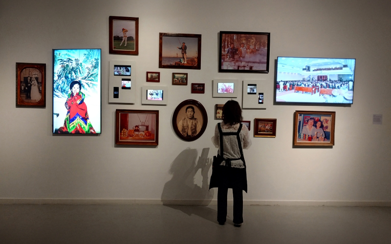 Una mujer de la comunidad coreana observa y fotografía la exposición | José Alirio Peña