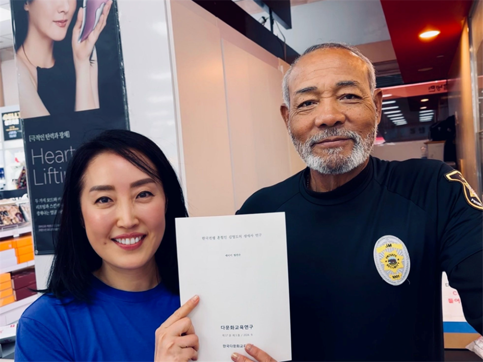 Con rostros felices, Amy Hutchinson presentó su tesis, "La historia de la vida de Young-do Kim, una persona mestiza de la Guerra de Corea", al Sr. Young-do Kim. | Amy Hutchinson